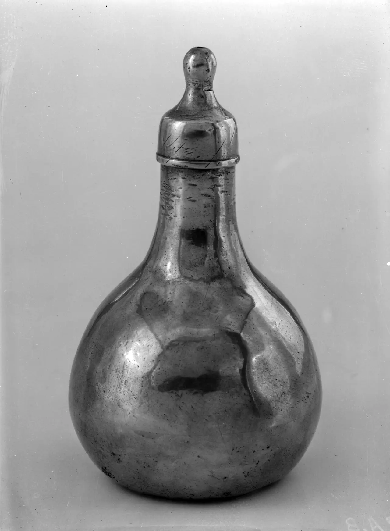 A metal baby bottle with a rounded body and narrow neck
