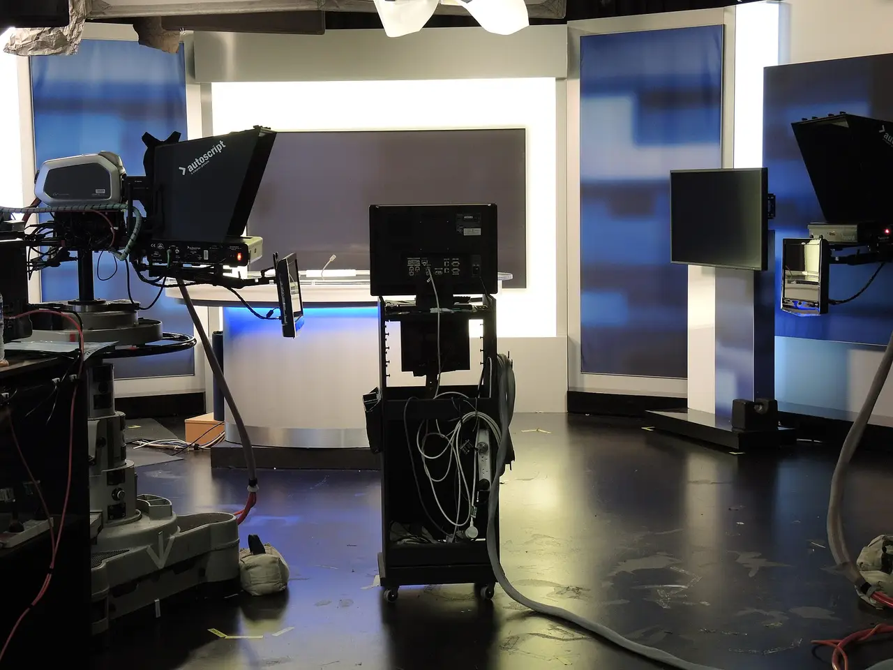 Empty television news studio with cameras and a blue backdrop