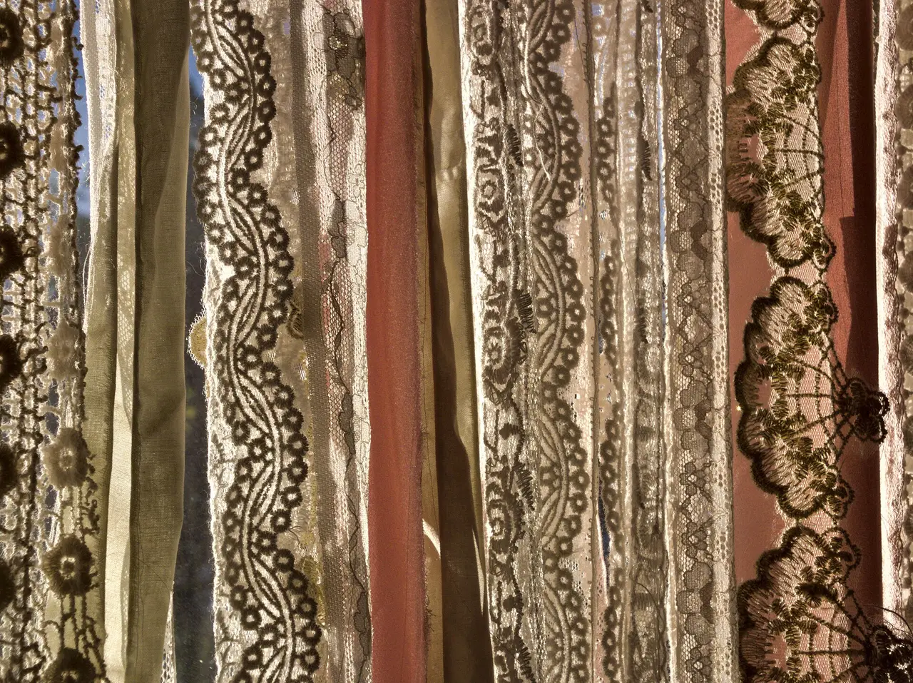 Hanging strips of patterned lace lit from behind by sunlight
