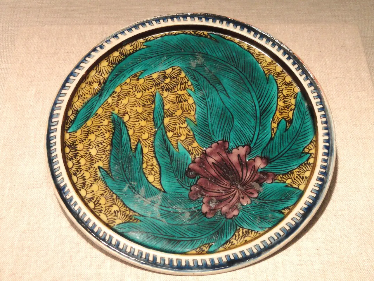 A round Japanese plate painted in green, gold and red