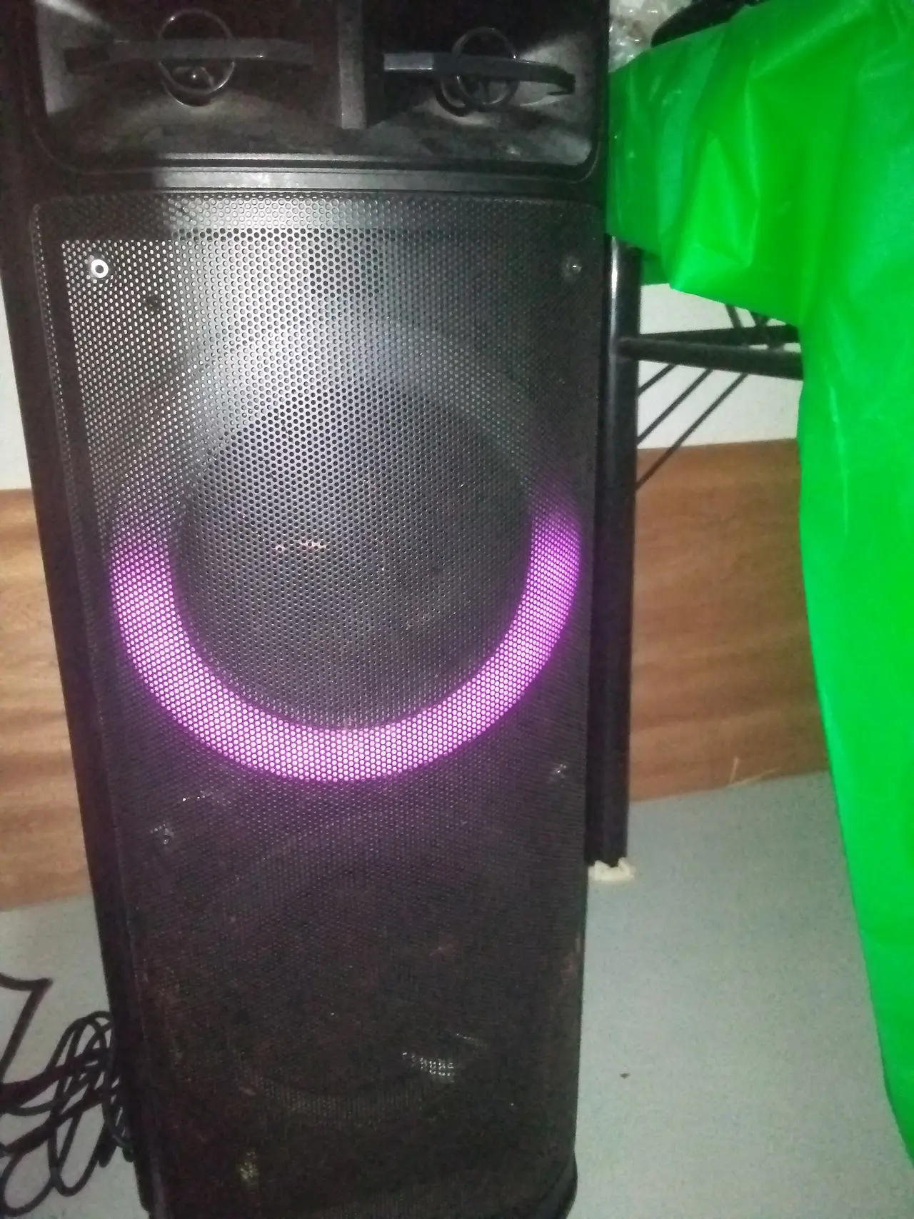 A tall black loudspeaker with a glowing purple ring around the cone