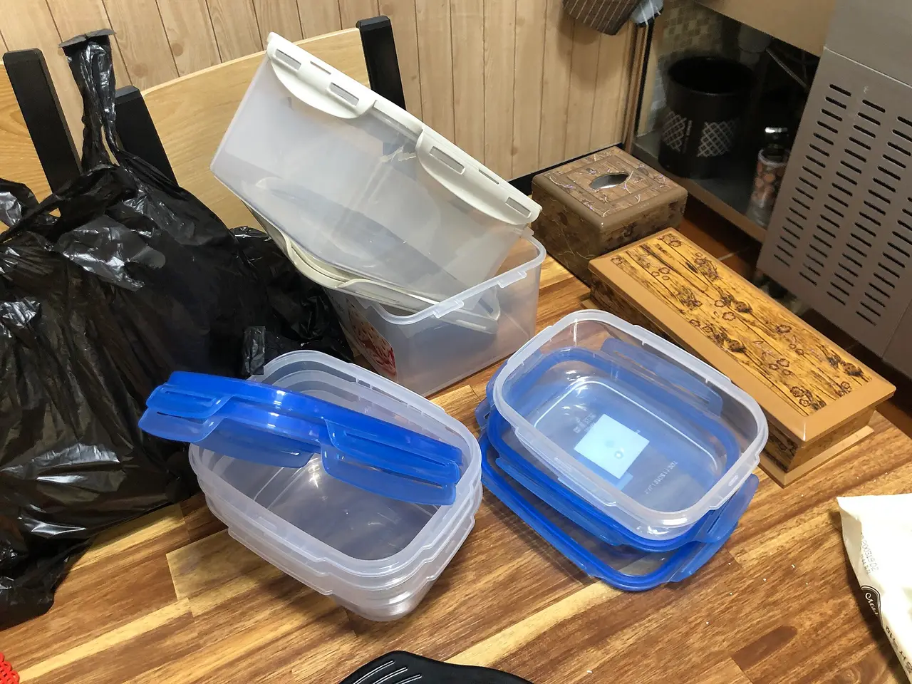 Clear plastic food containers with blue lids stacked on a table