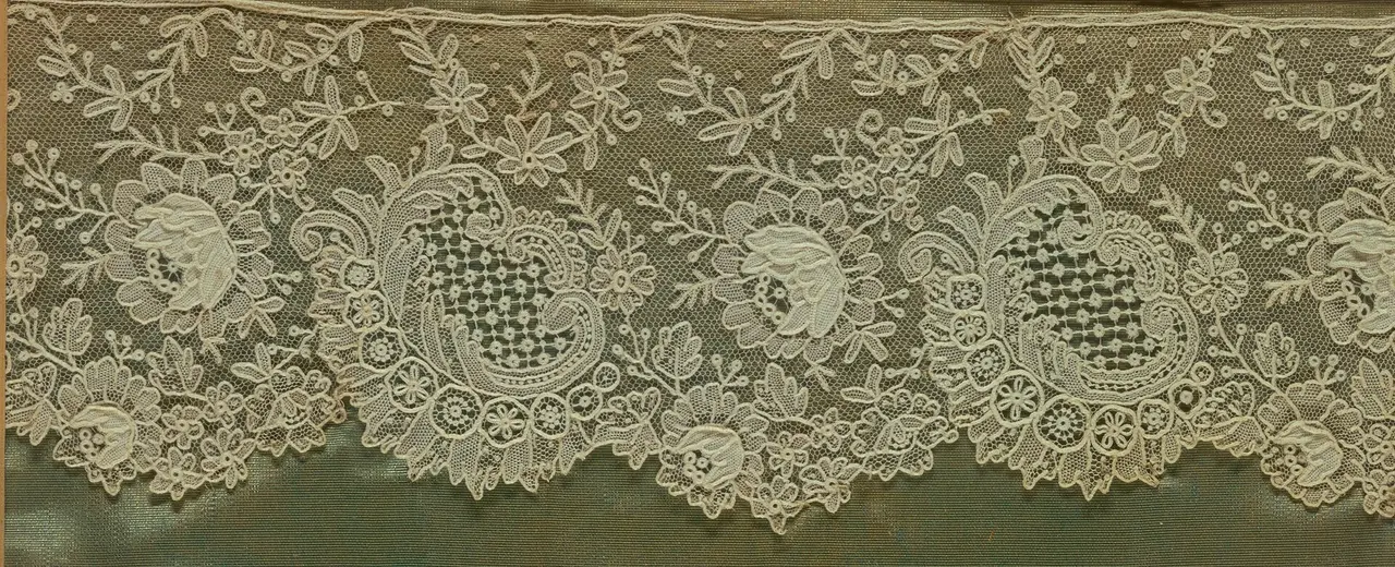 A strip of white lace with raised rose motifs