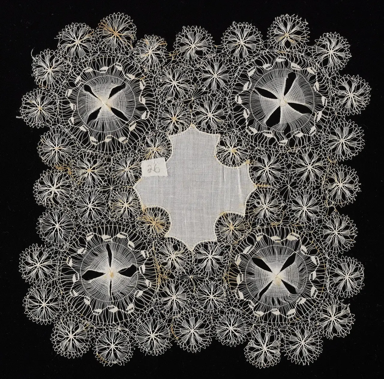 An ivory hairpin lace doily with round medallions on black