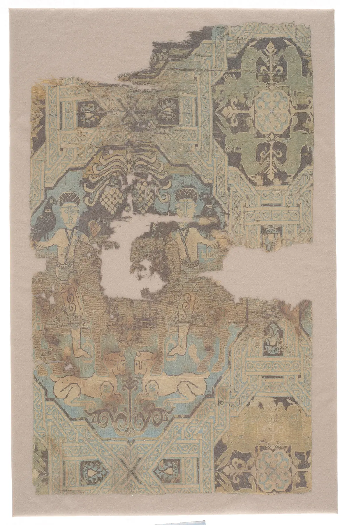 A torn piece of woven silk with figures and geometric panels