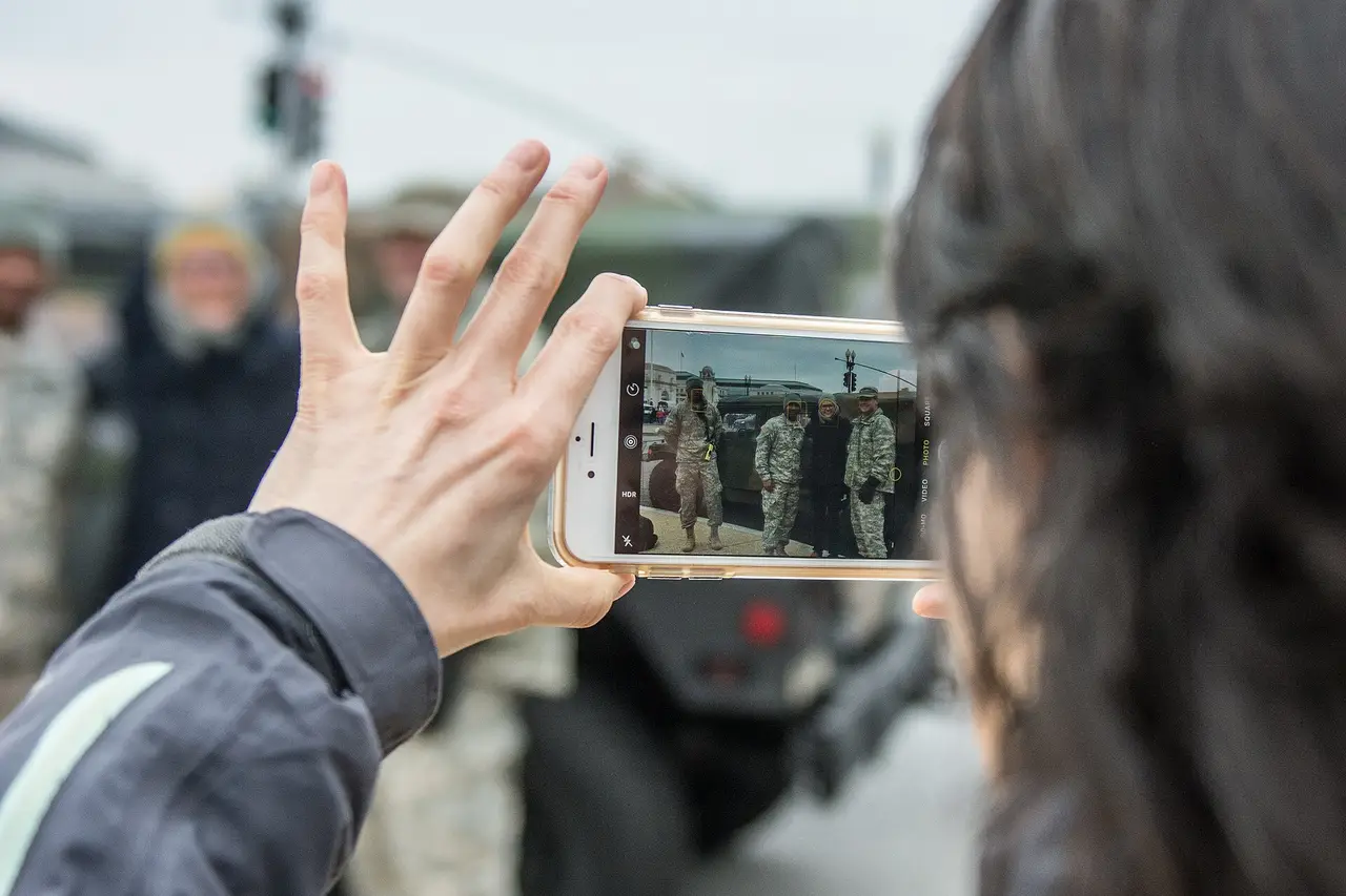 A raised hand holding a smartphone, the person's face turned away