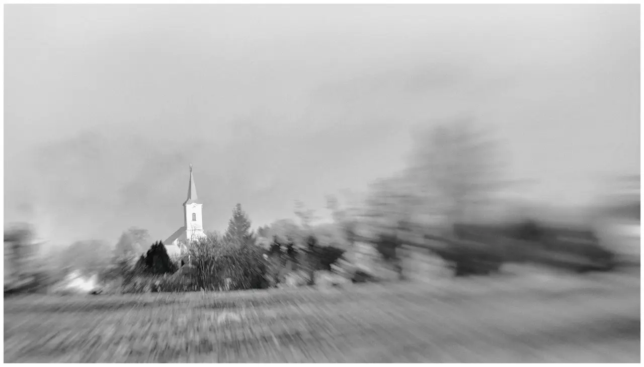 Black and white landscape of a church among trees with a blurred foreground