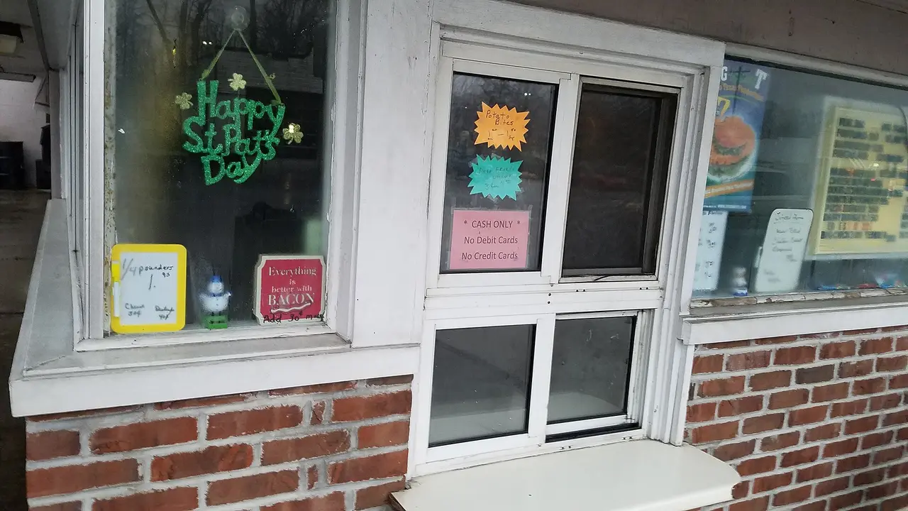 A small brick shop front with a window sign about cash only payment