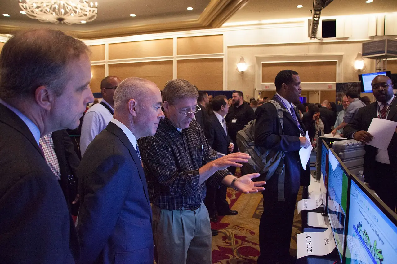 Men in suits gathered around screens at a job fair