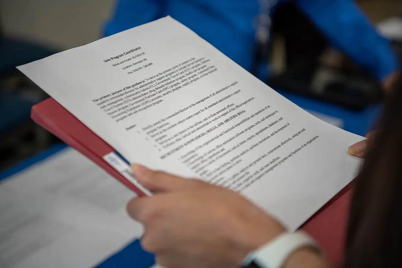 A hand holding a printed resume page over a red folder
