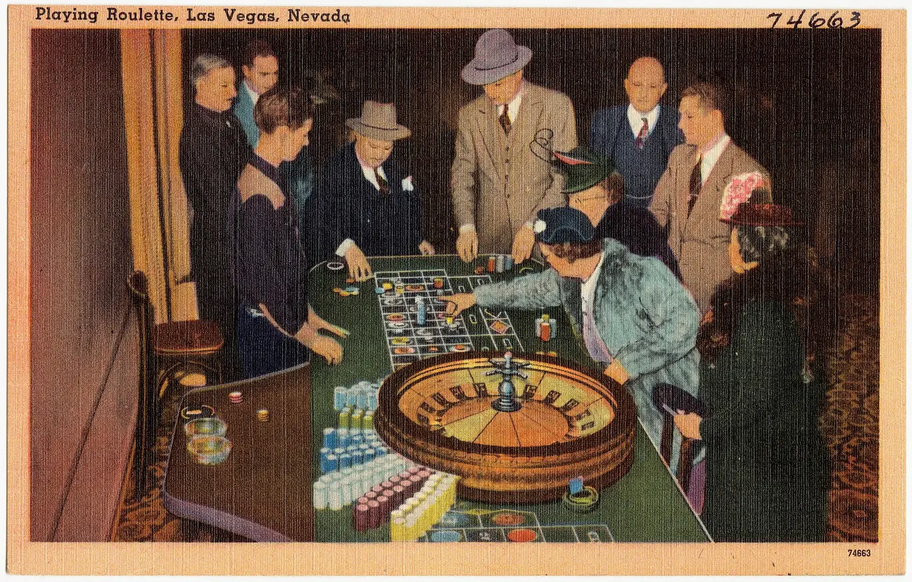People in hats and coats gathered around a roulette table in a casino