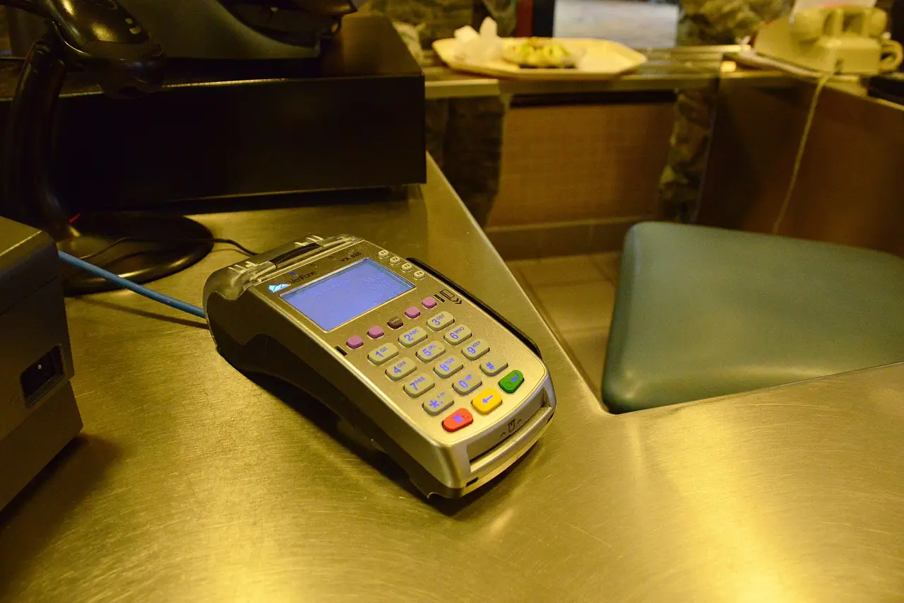 A card payment terminal with a keypad on a steel counter
