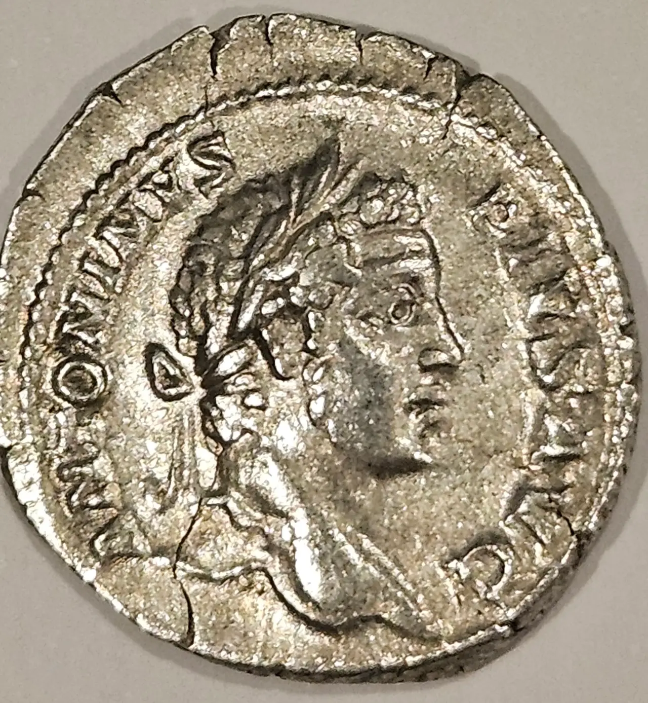 A worn silver Roman coin showing a crowned head in profile
