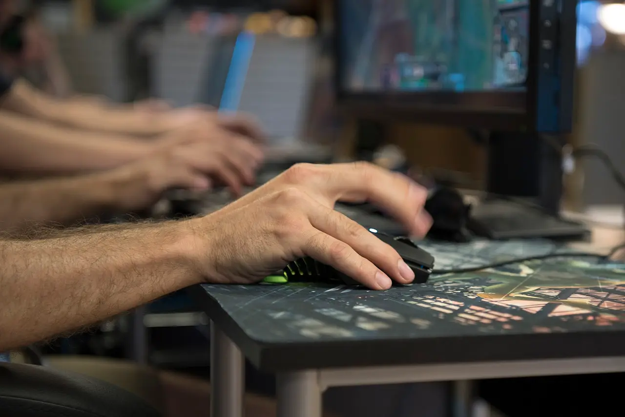 A hand on a computer mouse at a gaming tournament desk