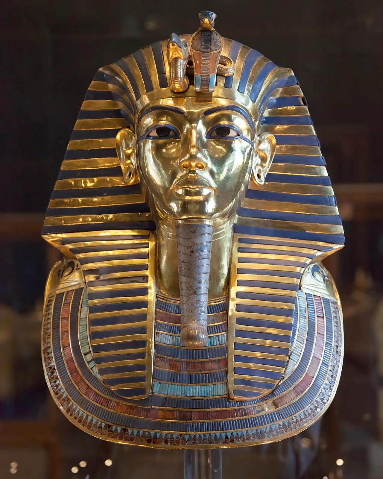 The gold and blue funerary mask of Tutankhamun in a museum case