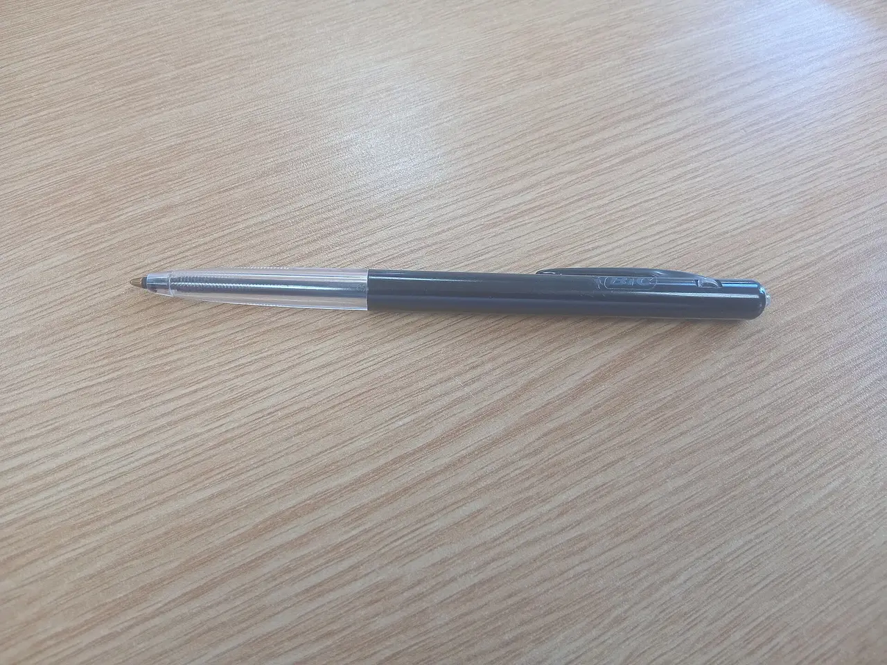 A grey pen lying on a wooden tabletop