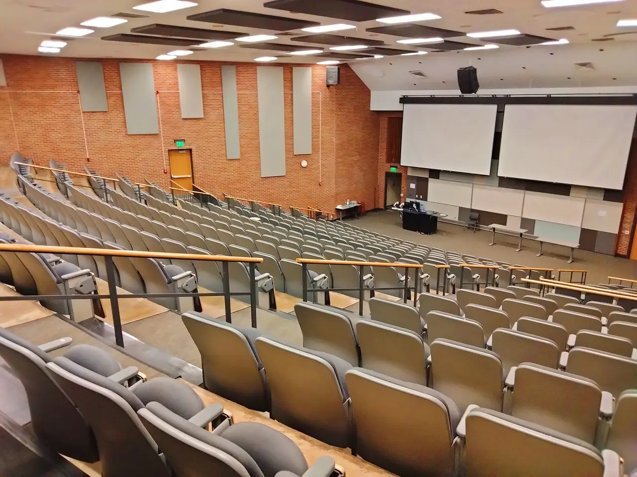 Empty tiered lecture hall with rows of seats and screens