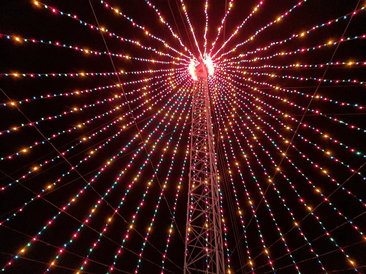 Lines of coloured lights spreading outward from a tower at night