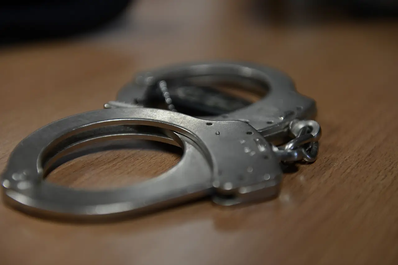 A pair of steel handcuffs on a wooden table