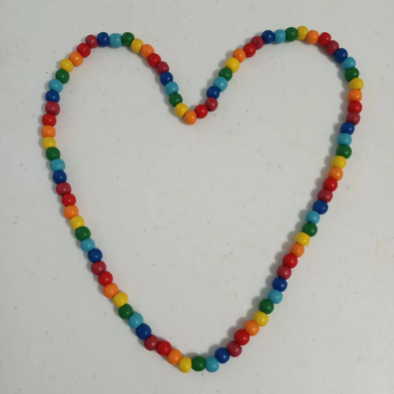 Rainbow-coloured beads arranged in a heart shape