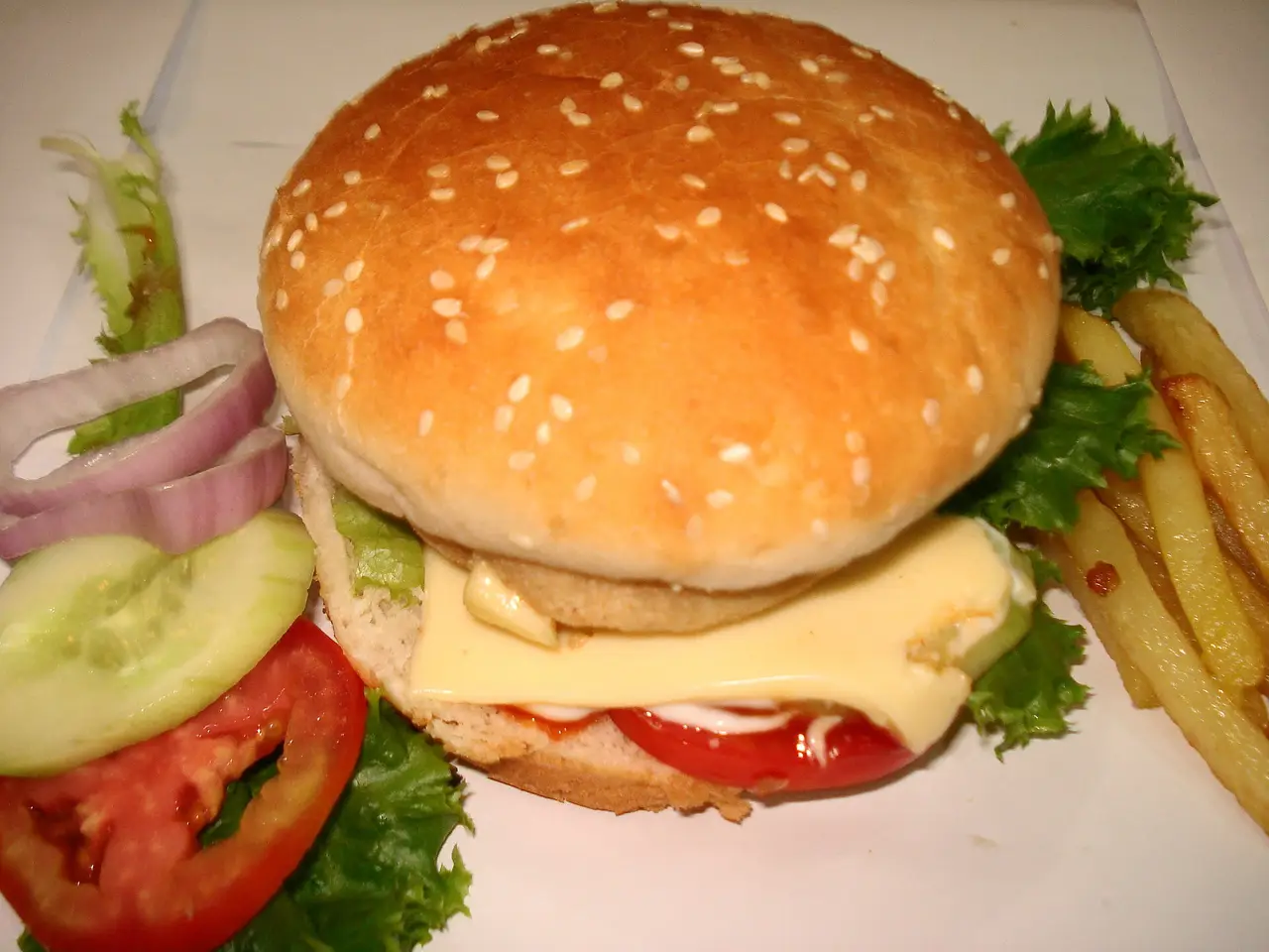 A cheeseburger in a sesame bun on a plate with chips