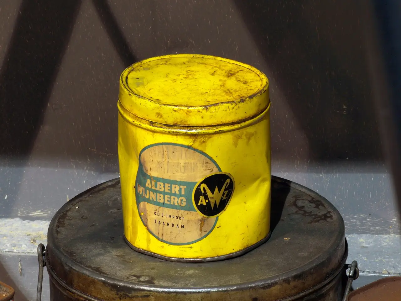 A yellow metal tin with a label, standing on a dark surface