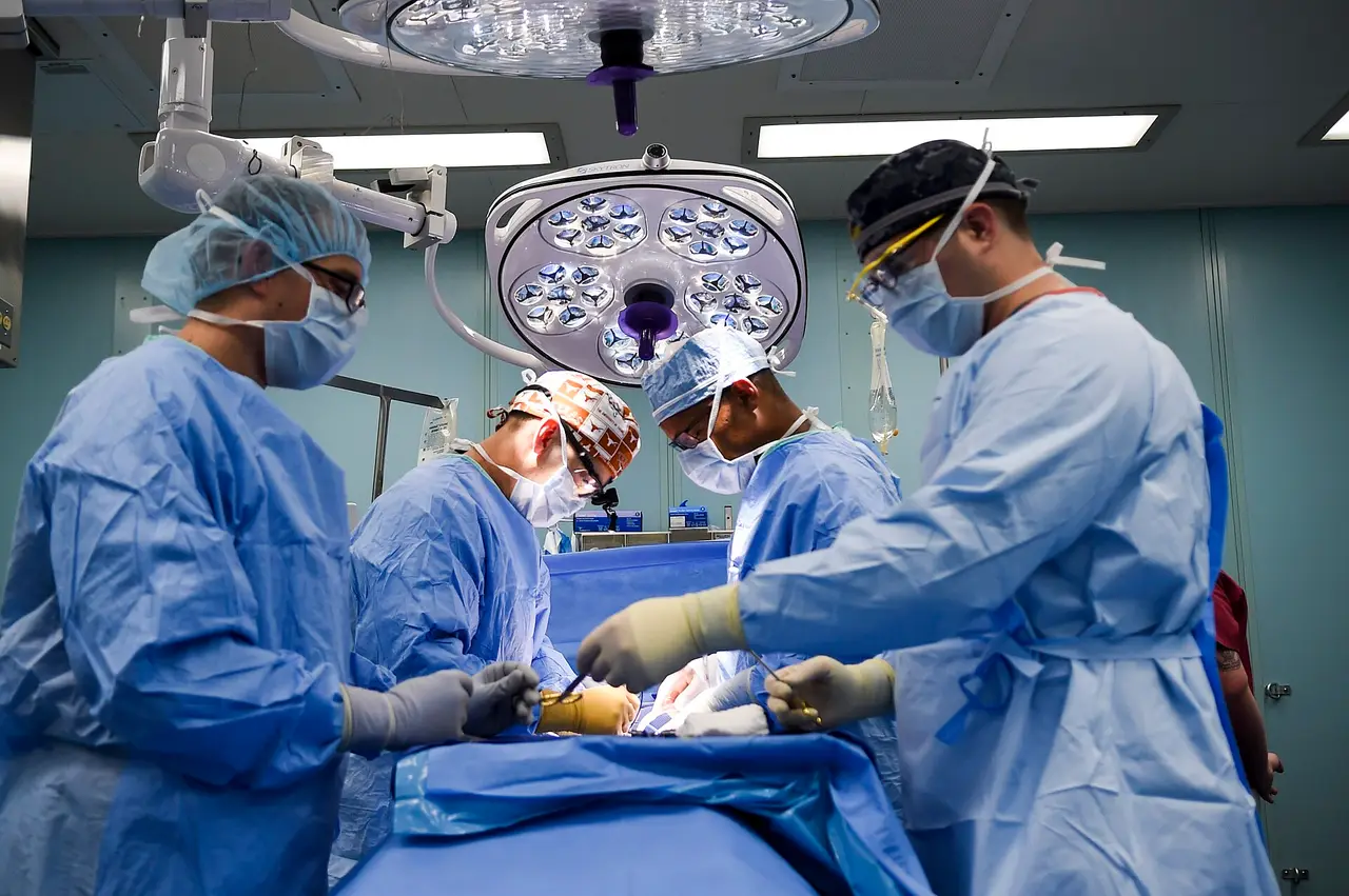 Surgeons in blue gowns operating under bright lights