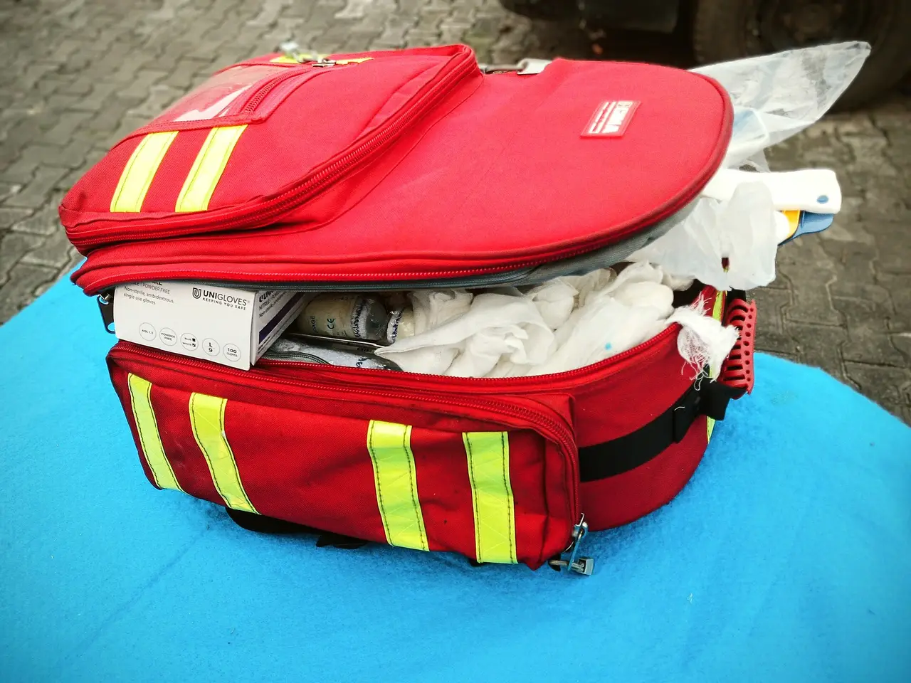 An open red first aid bag with reflective stripes and supplies