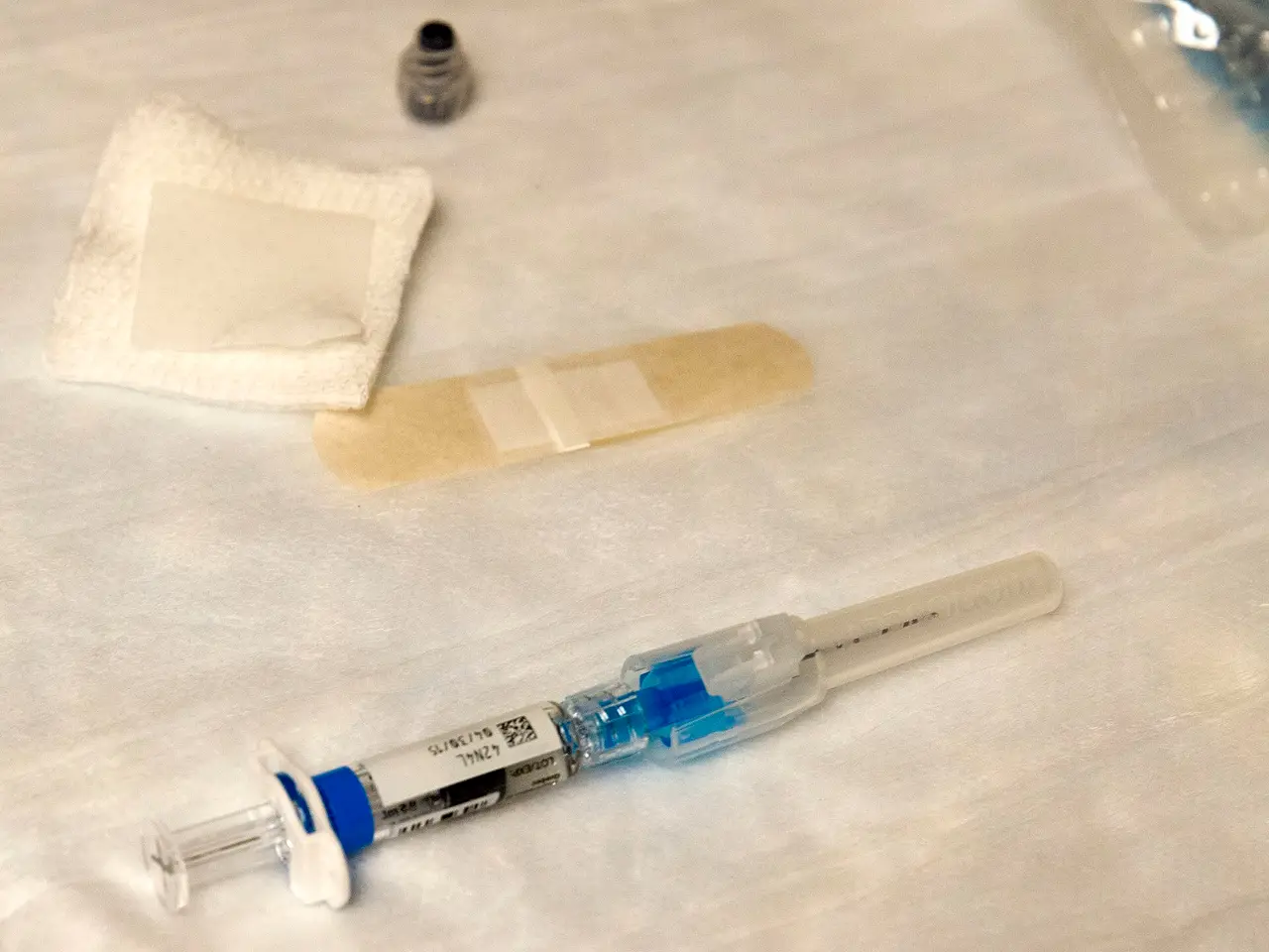 A vaccine syringe, gauze pad and plaster on a table