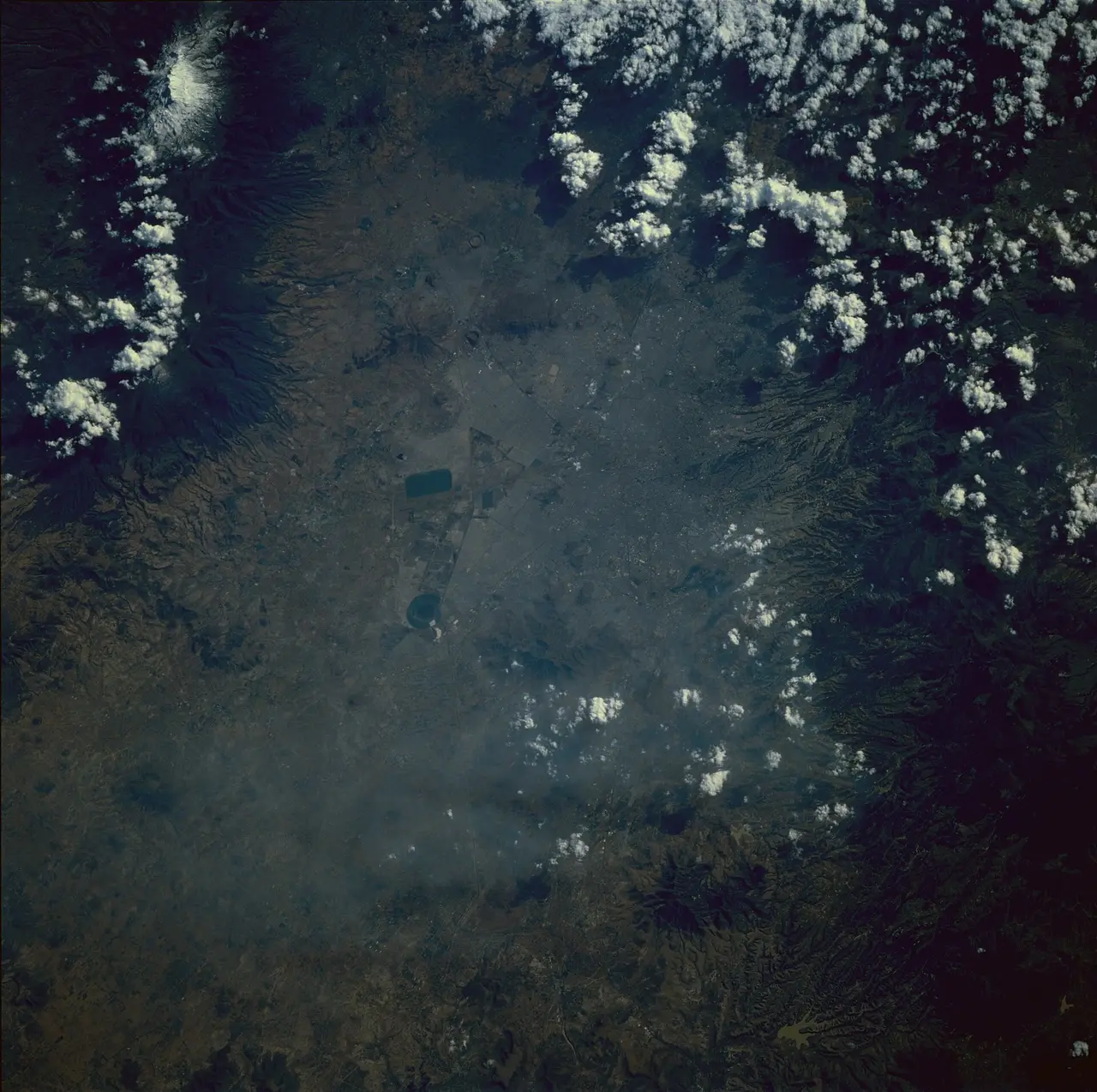 A grey haze of smog seen from above with small white clouds