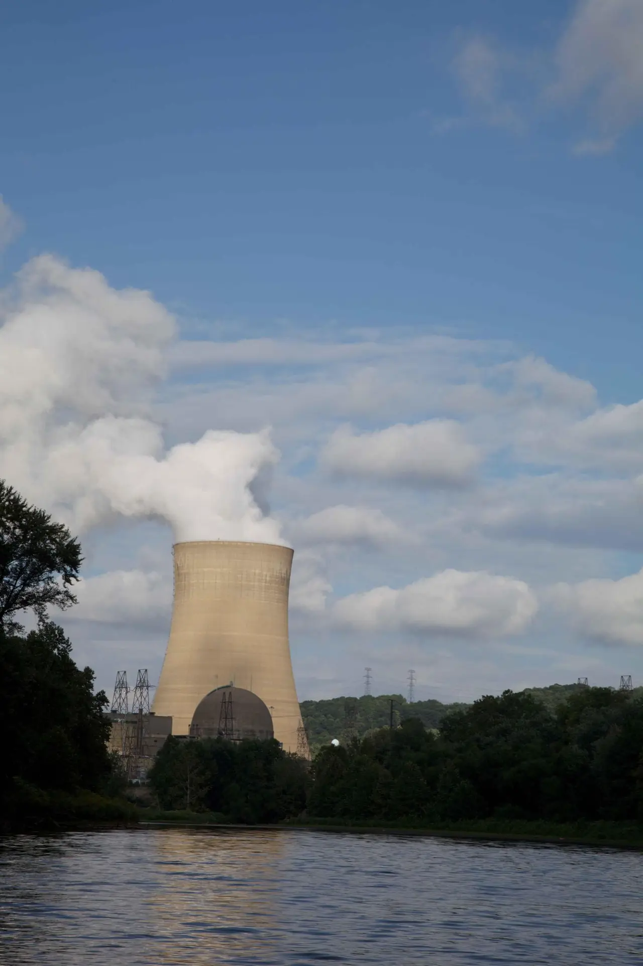 Steam rising from a power plant cooling tower beside a river