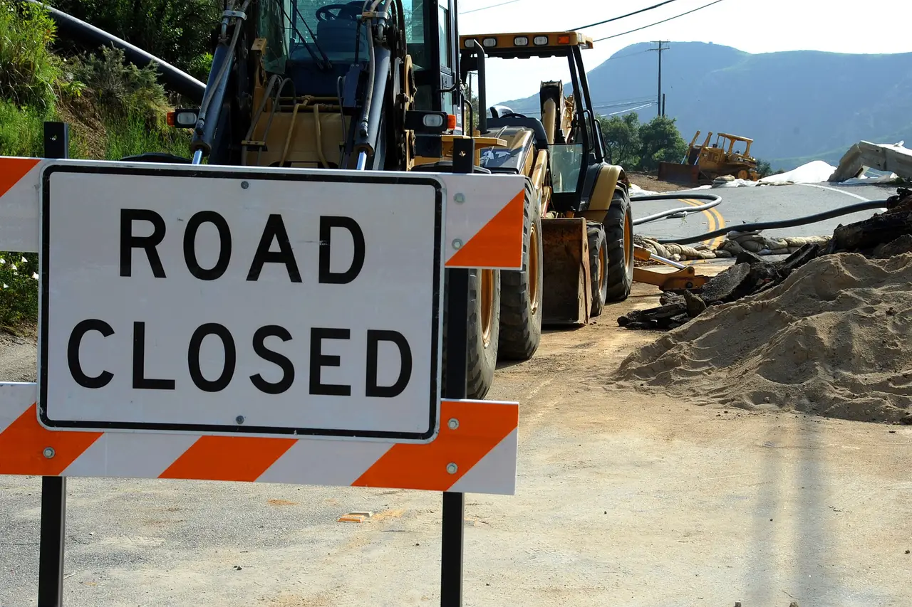 A Road Closed sign on a barrier in front of construction machinery