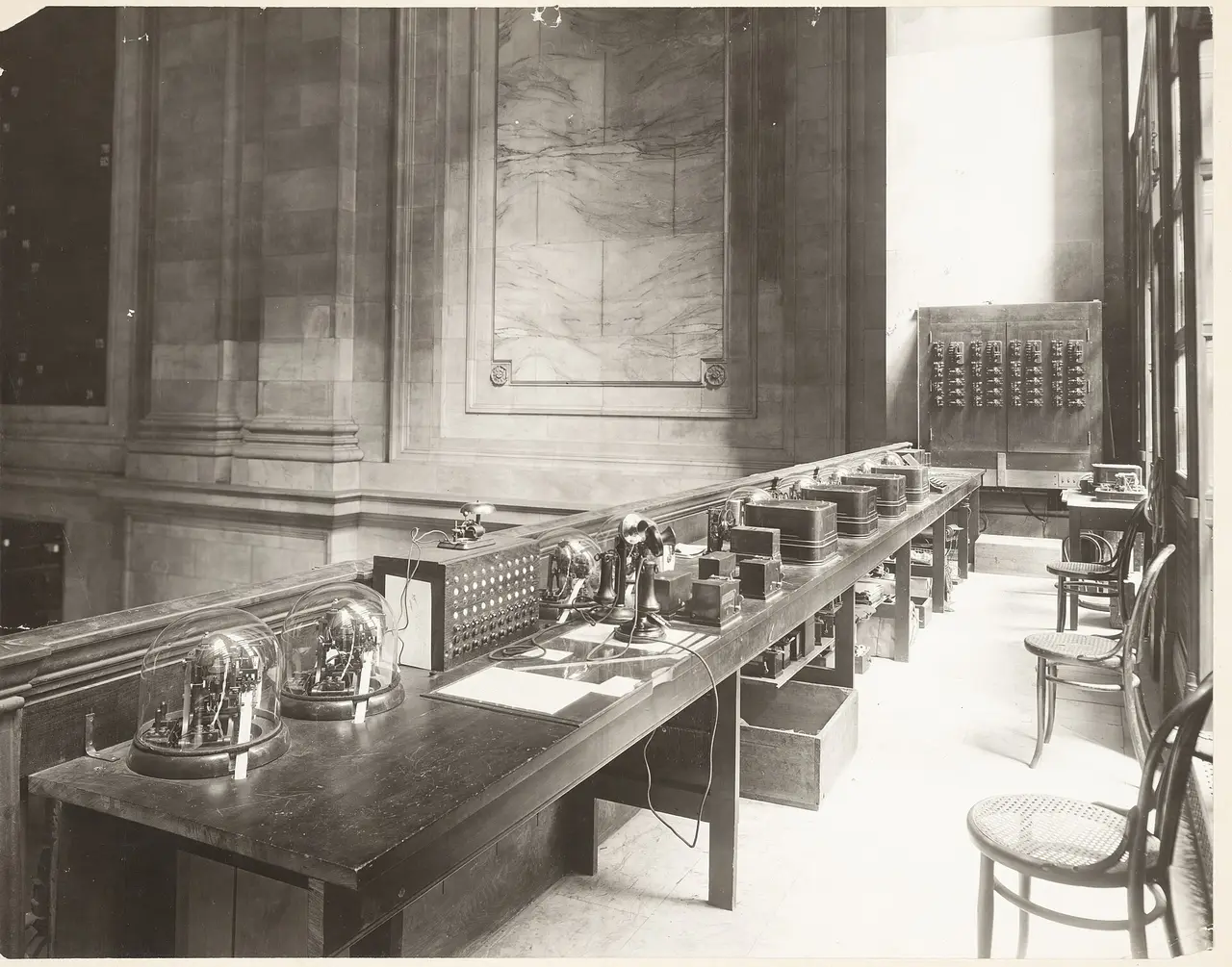 A long table of ticker machines with glass domes in a large room
