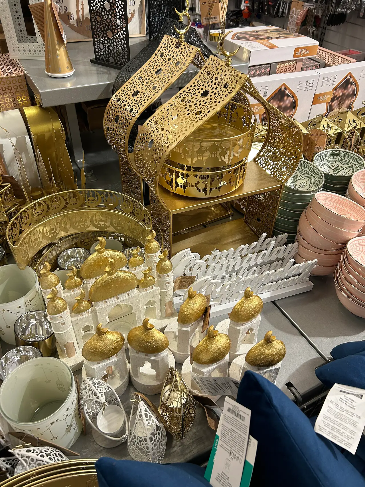 Gold-coloured lanterns and glasses arranged on shop shelves