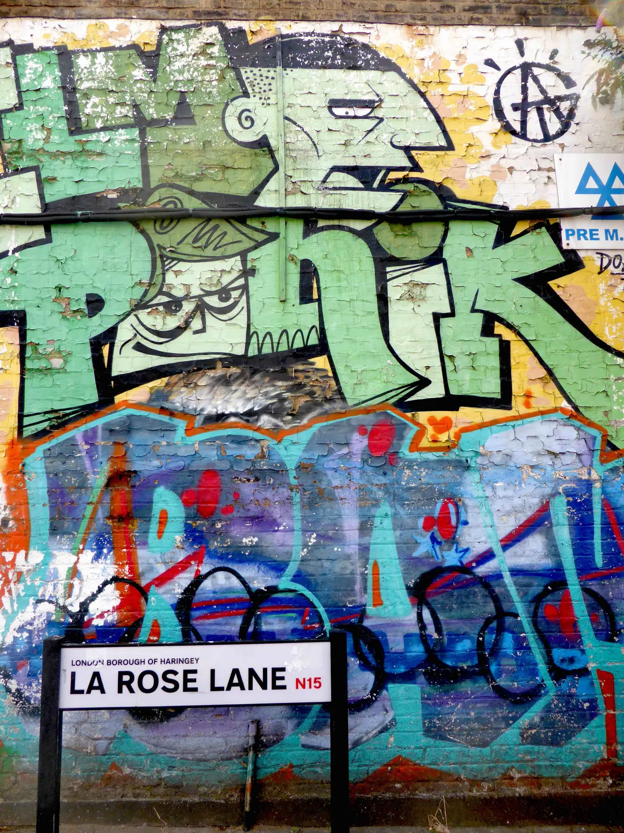 A wall covered in green and blue spray-painted lettering