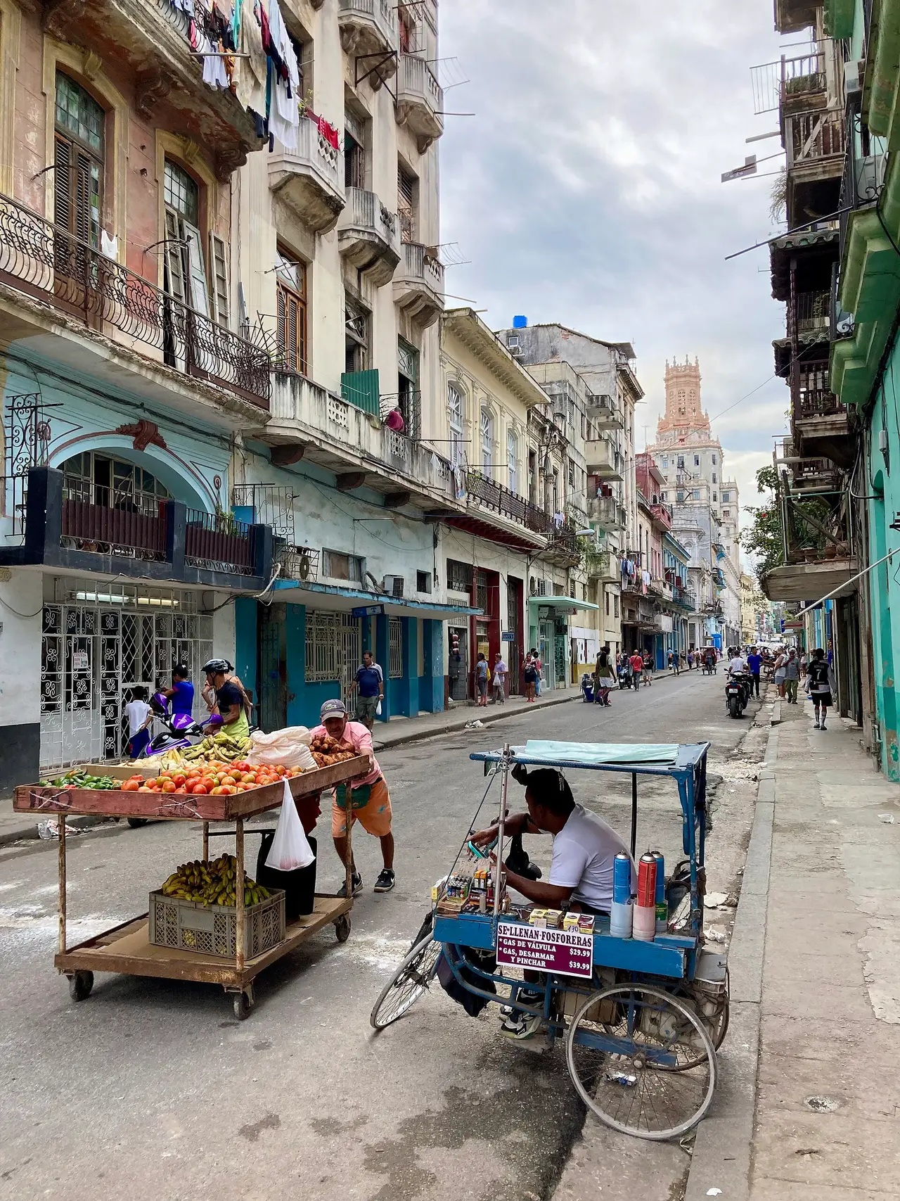 A vendor's cart and a cycle rickshaw on a Havana street