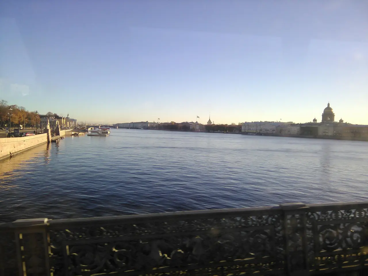 A broad river seen from an iron bridge railing at dusk