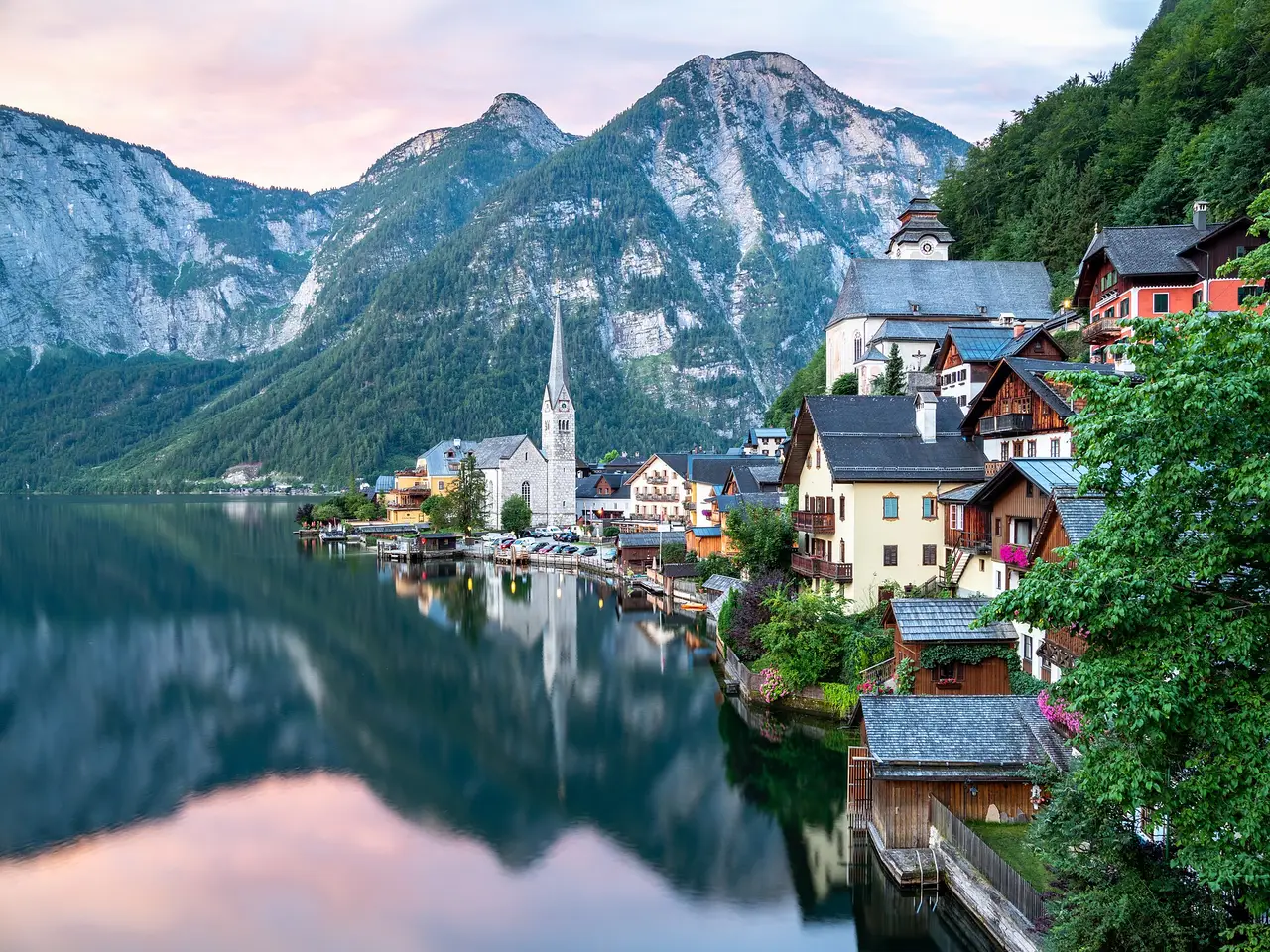 A lakeside village and church reflected in calm water beneath mountains