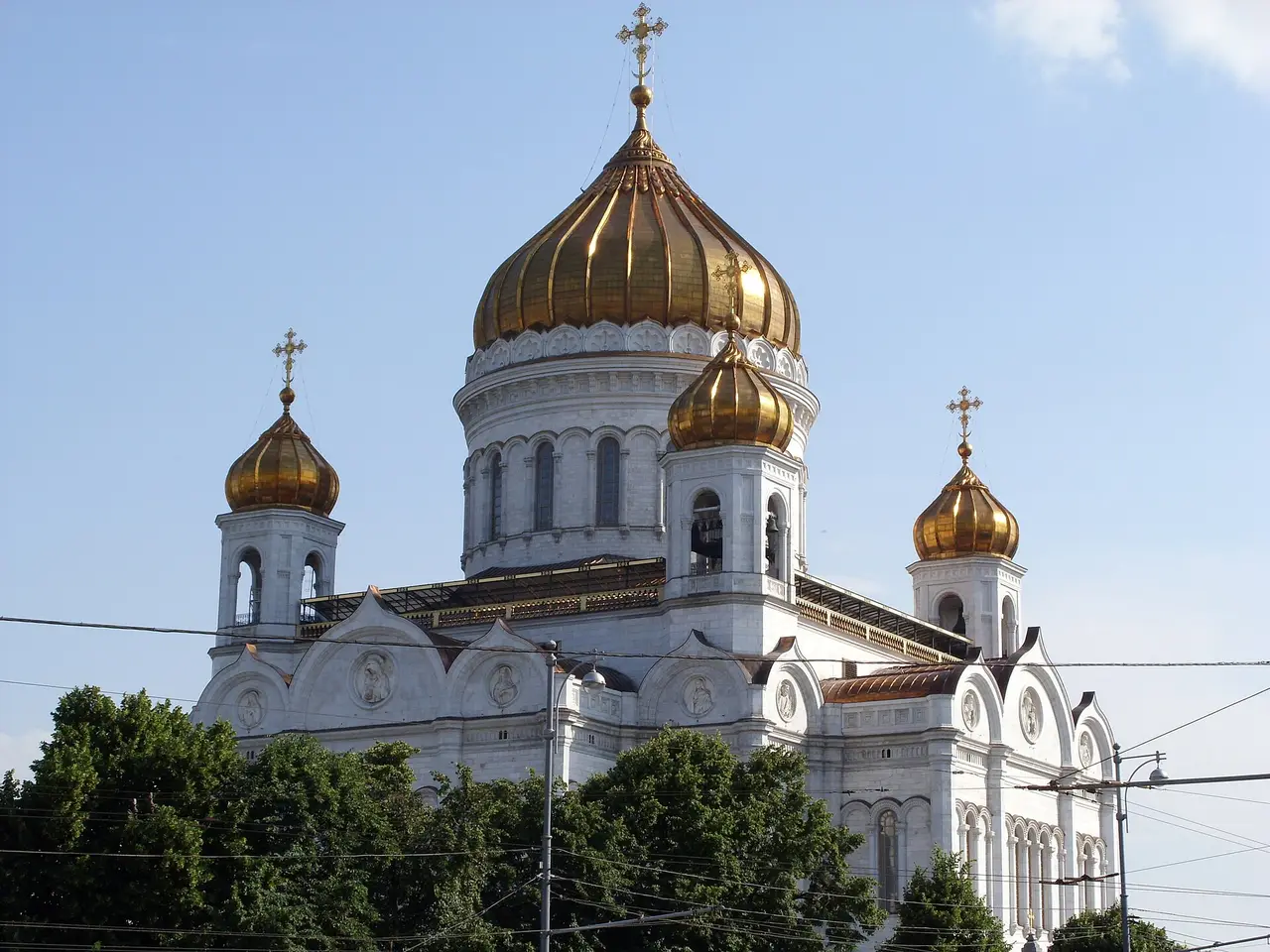 A white cathedral with golden domes under a blue sky