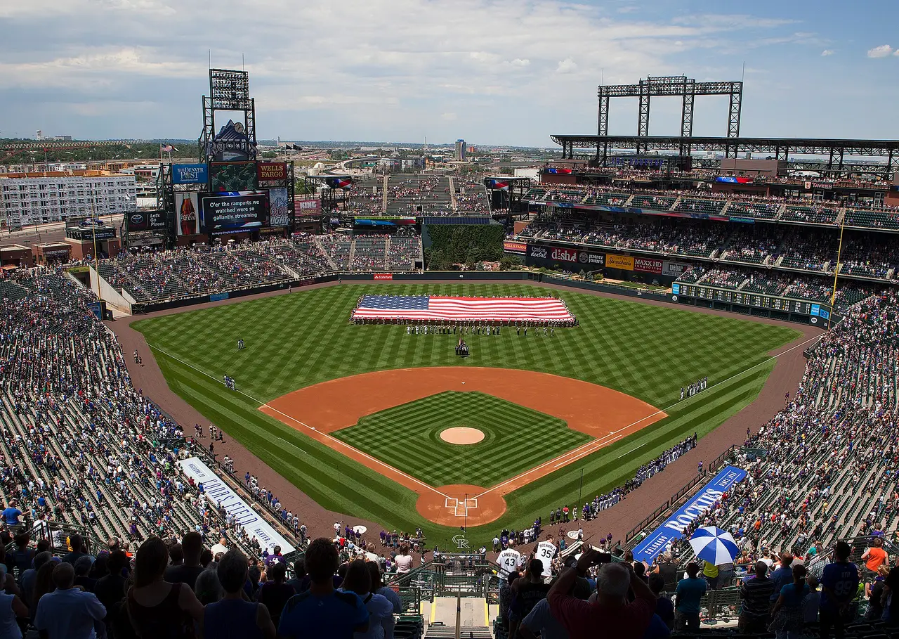 Aerial-style view of a full baseball stadium with a large flag on the outfield