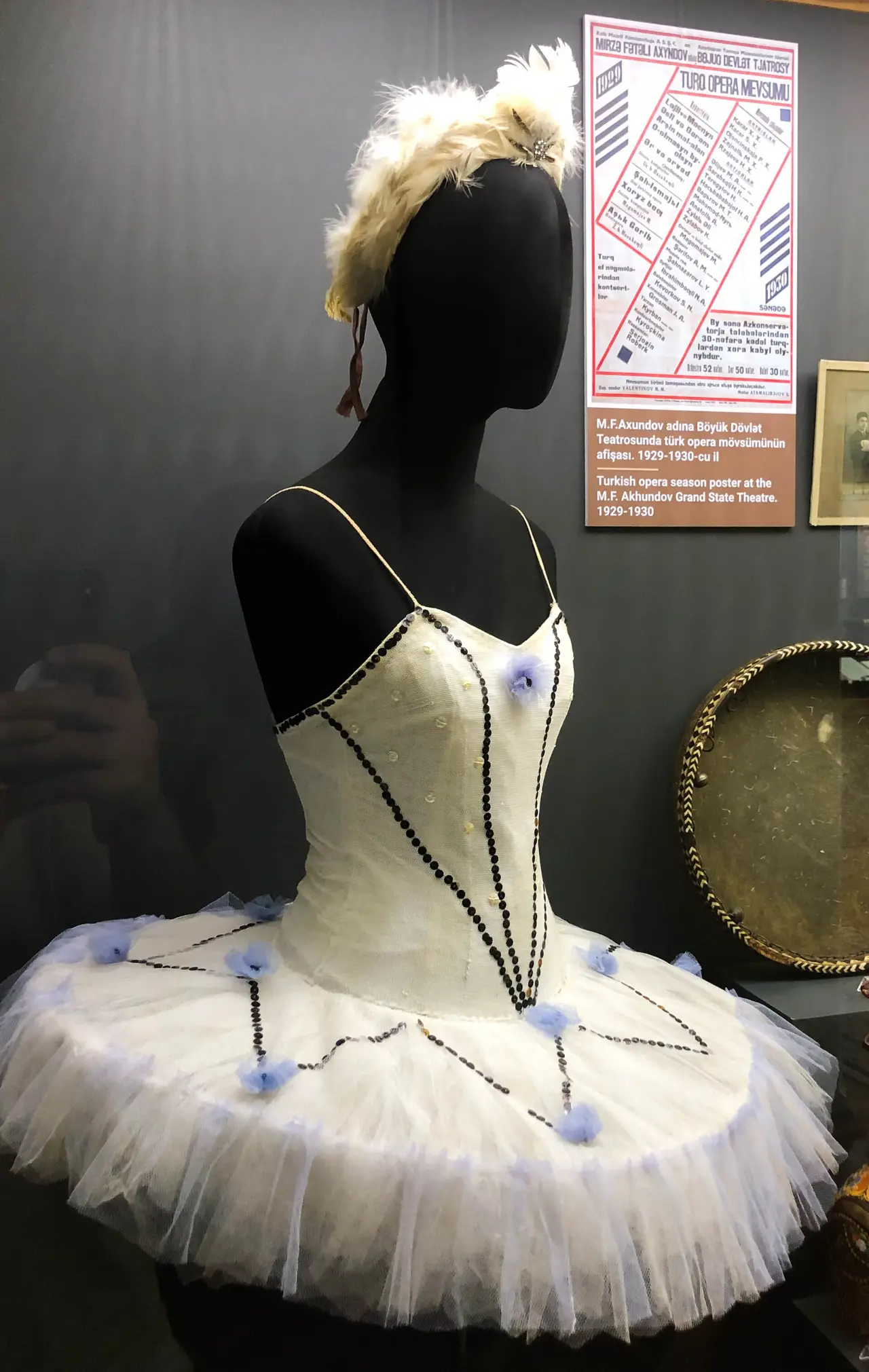 A white ballet tutu with a feathered headpiece on a display mannequin