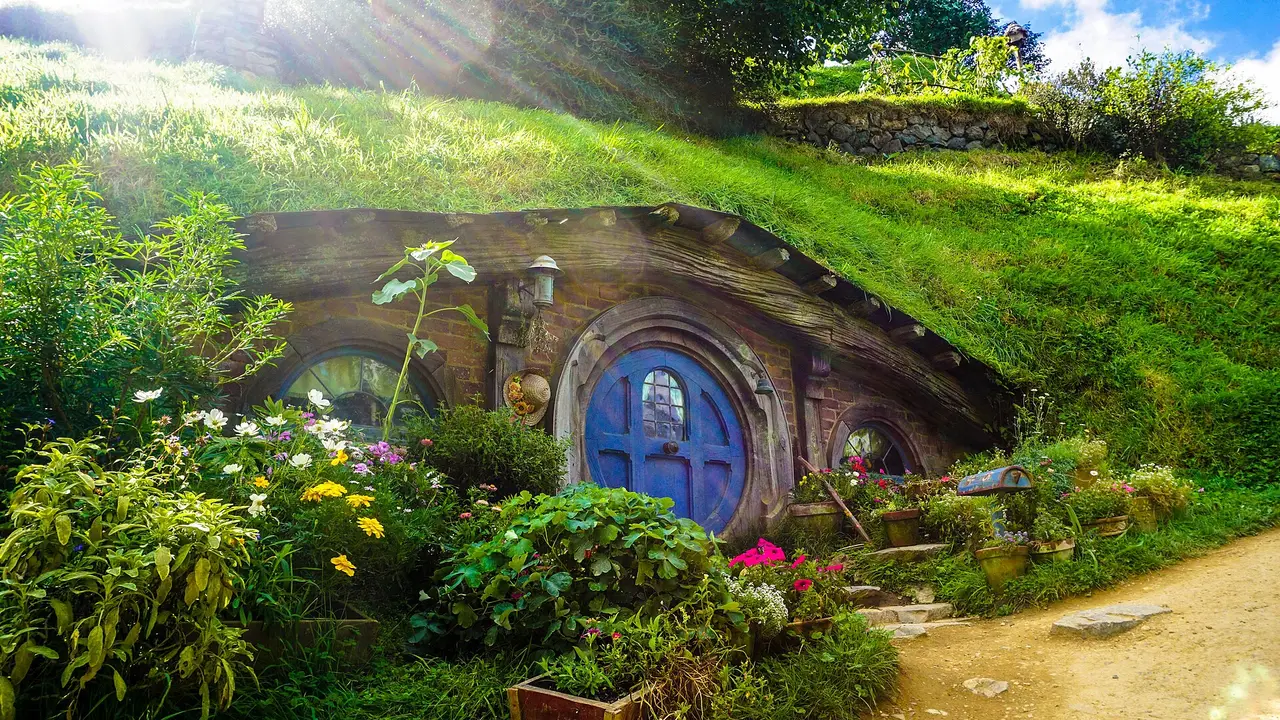 A round blue door in a green hillside surrounded by flowers