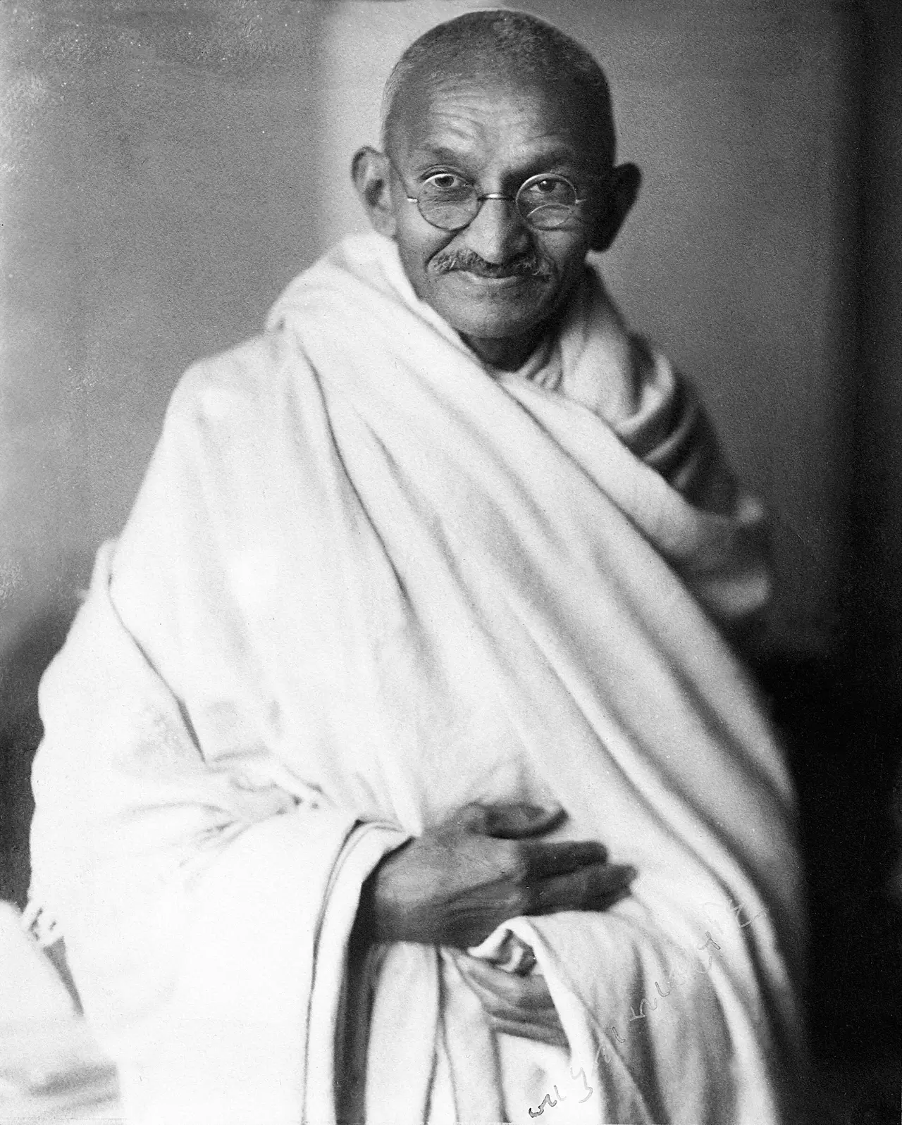 Black and white studio portrait of Gandhi in a white shawl
