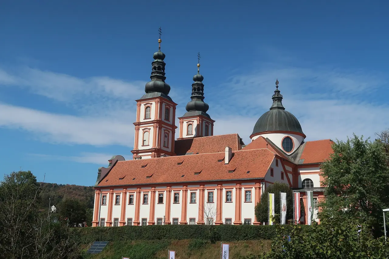 A white and red pilgrimage basilica with two towers under blue sky