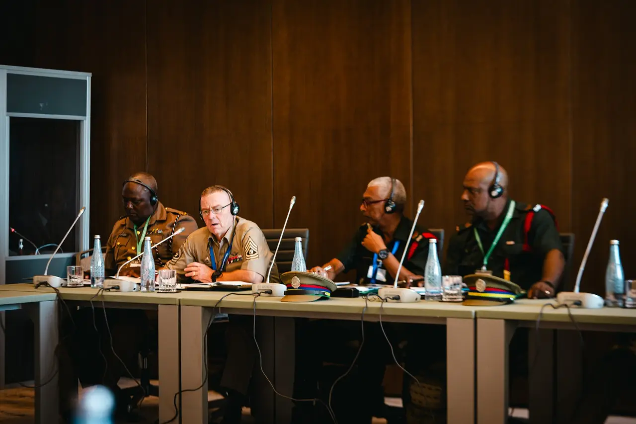 A row of delegates with headsets seated at a long conference table