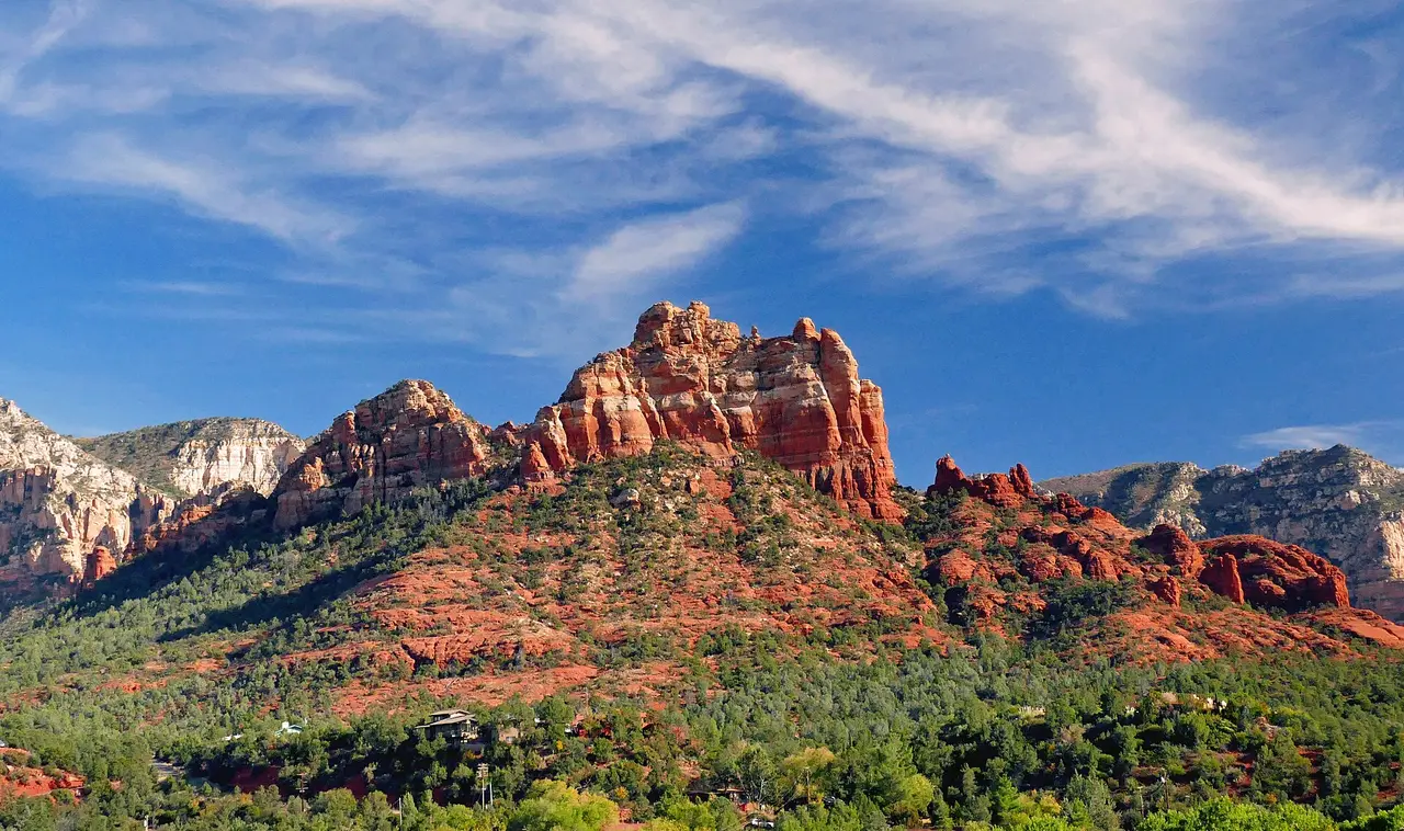 Red sandstone rock formations above green trees under a blue sky