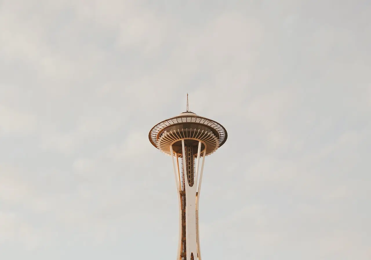 The Space Needle tower and its round deck against a pale sky