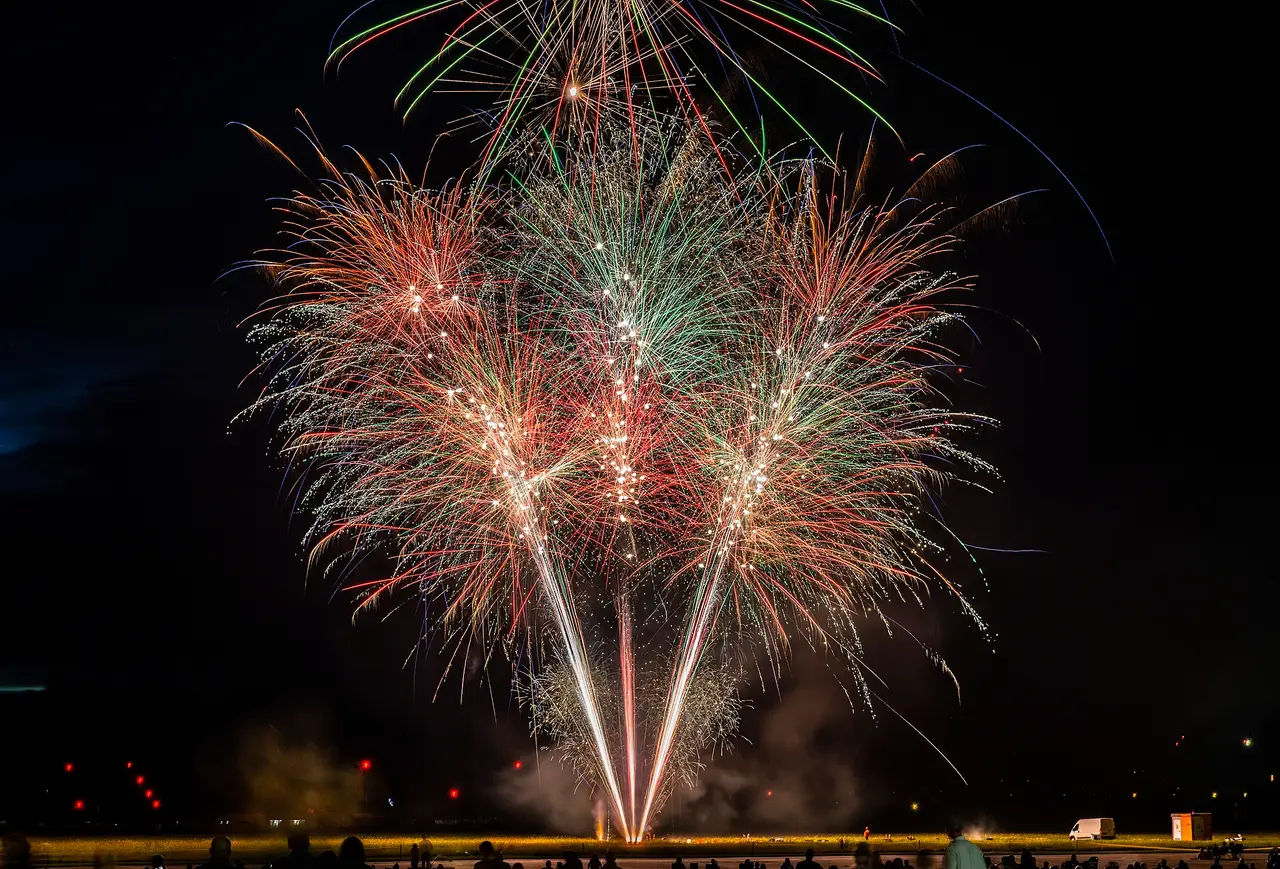 Red, green and white fireworks bursting in a dark night sky