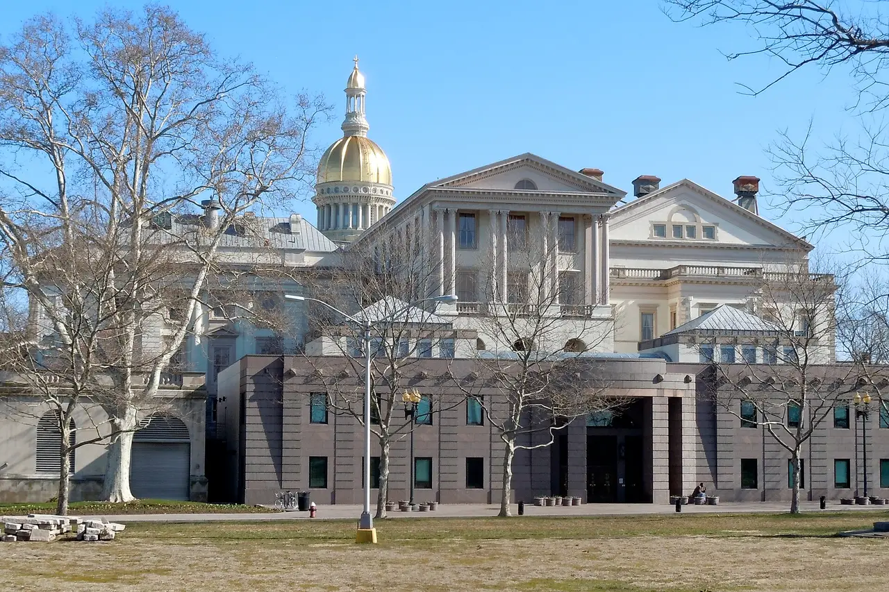 The New Jersey State House with a gold dome behind bare trees