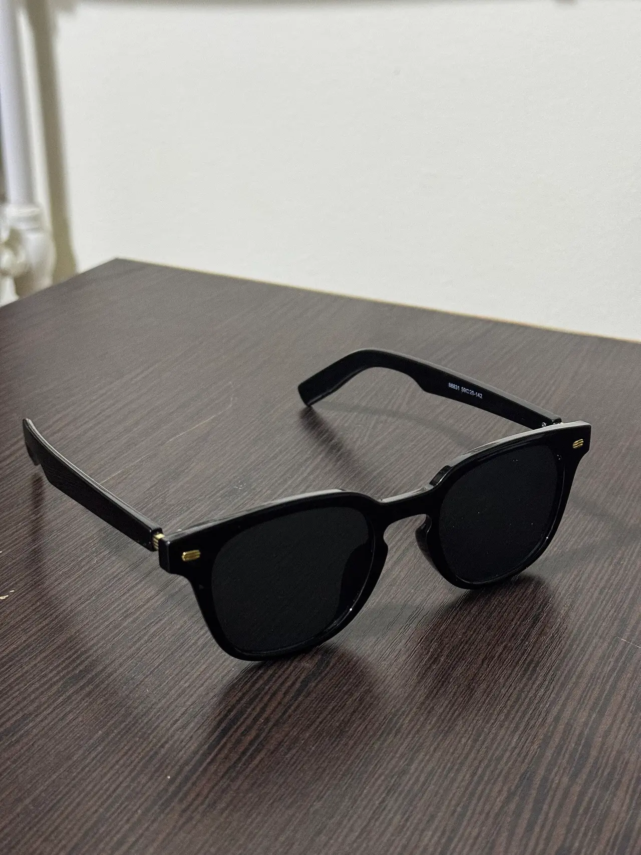 Black sunglasses lying on a dark wooden table